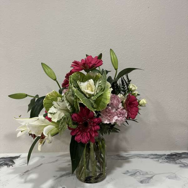 Mixed pink and white flowers arranged in a clear glass vase