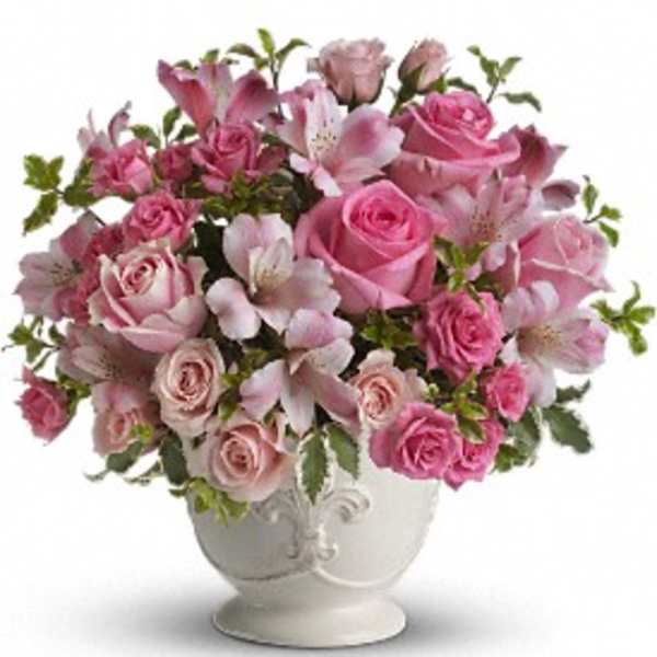 Pink roses and alstroemeria arranged in a white ceramic urn-style vase
