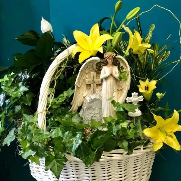 White basket arrangement with yellow lilies and an angel statue