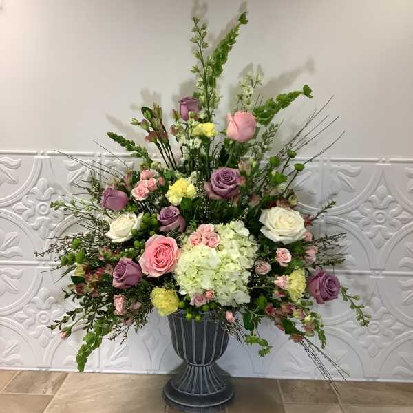 Large mixed flower arrangement in a dark pedestal vase