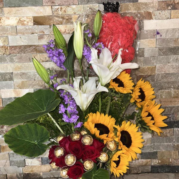 Tall mixed bouquet with red roses, white lilies, sunflowers, and purple flowers