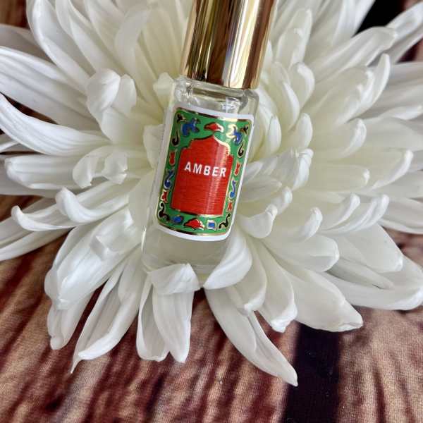 White flower with a small perfume bottle labeled Amber in the center
