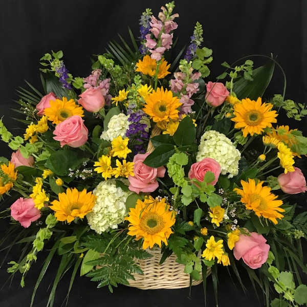 Basket arrangement of pink roses, sunflowers, and white hydrangeas