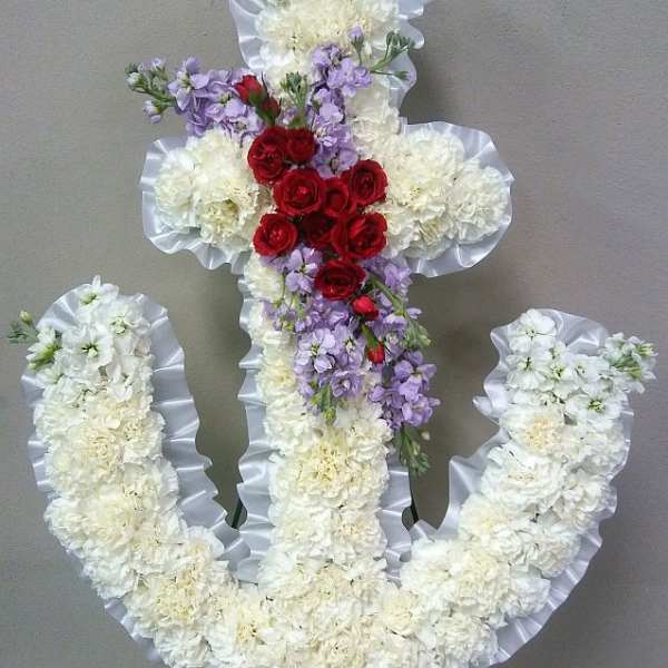 Floral cross arrangement with white flowers, red roses, and lavender blooms