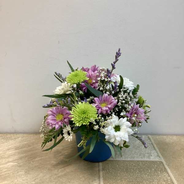Mixed bouquet of pink, white, and green flowers in a blue container