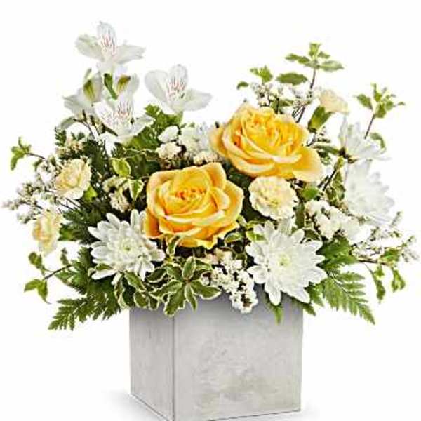 Arrangement of yellow roses and mixed white flowers in a gray cube vase