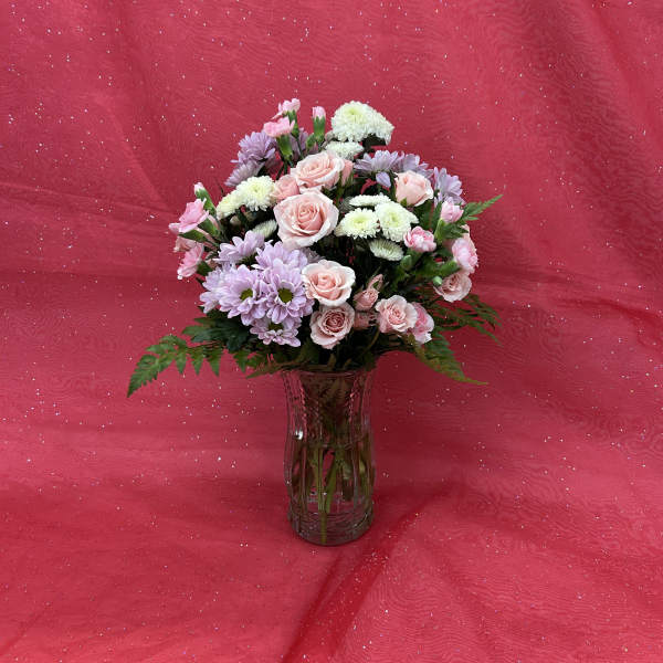 Pink and lavender flowers arranged in a glass vase