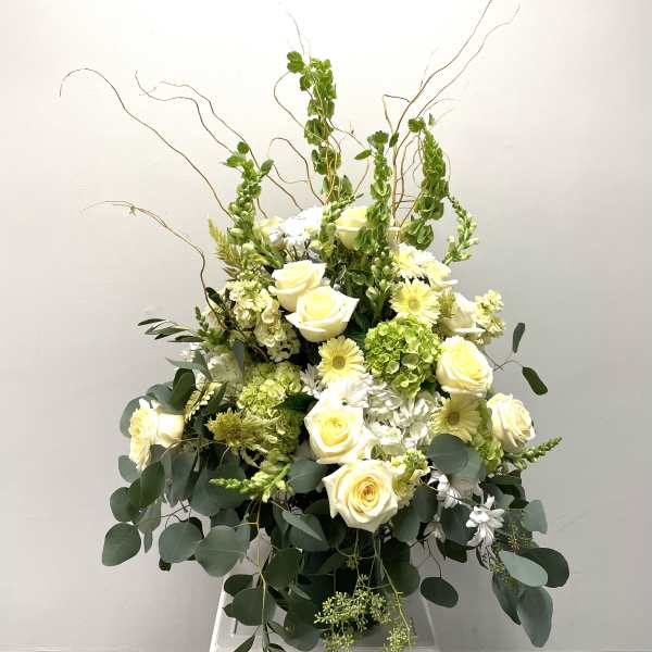 Tall white and pale yellow floral arrangement with roses and daisies