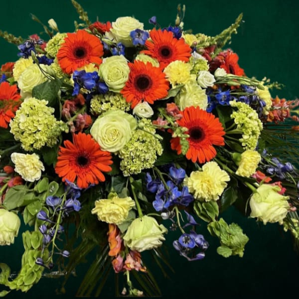 Large bouquet of orange gerbera daisies, pale roses, and blue flowers