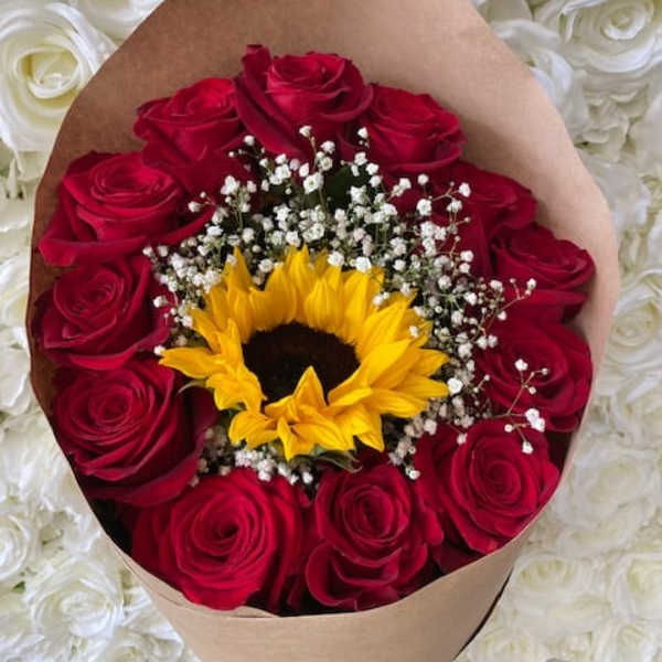 Bouquet of red roses with a sunflower and baby's breath in brown paper