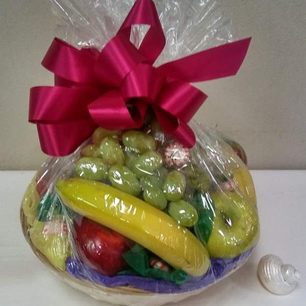 Gift basket of assorted fruit wrapped in clear cellophane with a pink bow