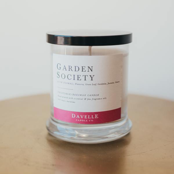 Glass jar candle with a black lid and floral label