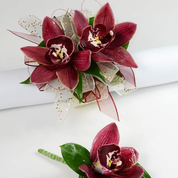 Two burgundy orchid corsages with ribbon accents