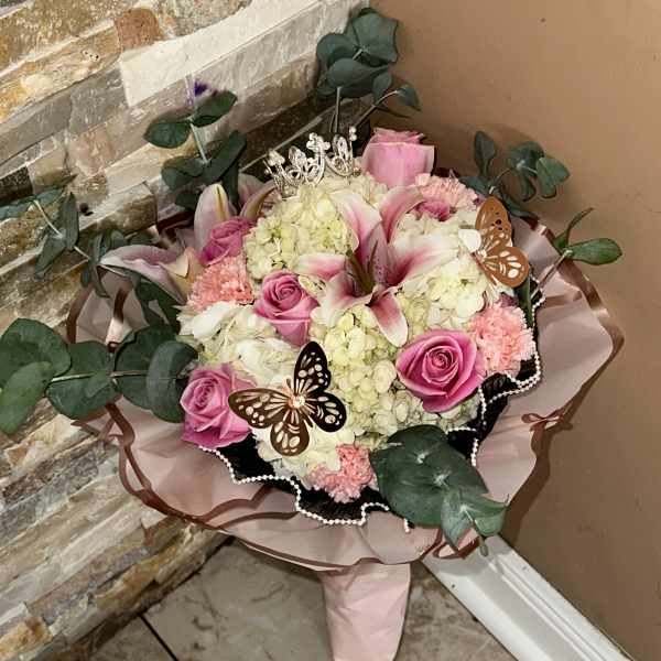 Pink roses and lilies arranged with hydrangeas and decorative butterflies
