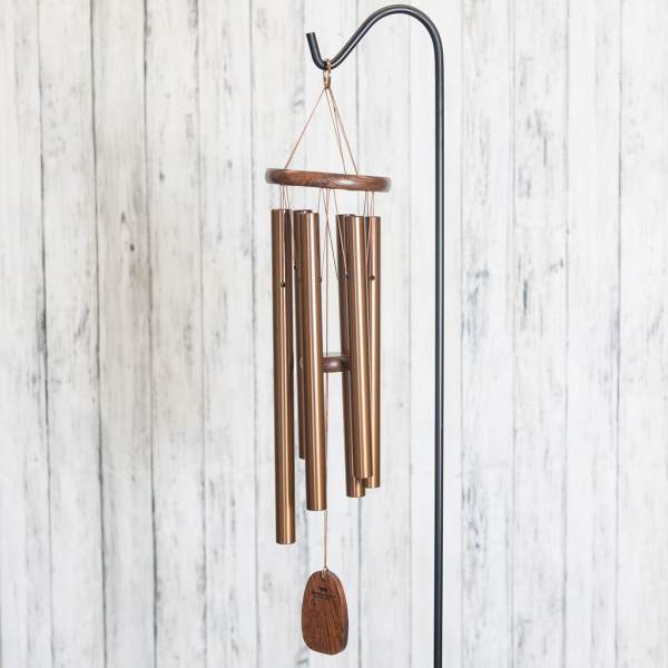 Copper wind chime hanging from a black stand