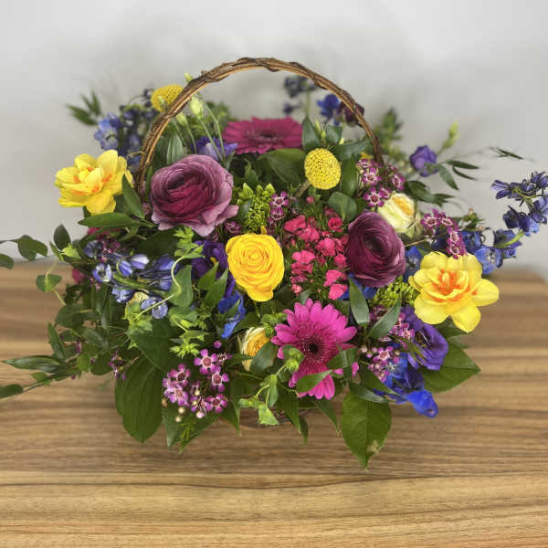 Colorful mixed flower basket with a woven handle