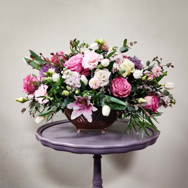 Pink and white mixed flower arrangement in a brown bowl on a purple stand