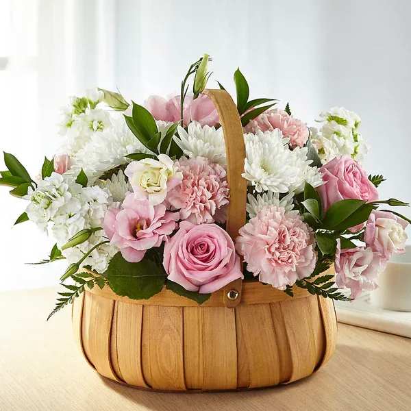 Pink and white flowers arranged in a wooden basket