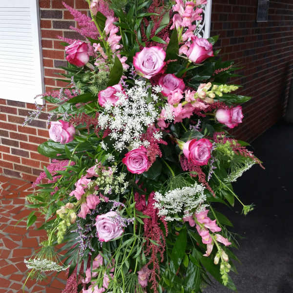 Tall standing spray of pink roses and snapdragons with white filler flowers