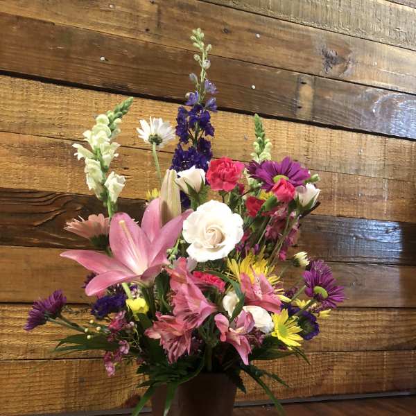 Mixed bouquet in a brown vase with pink lilies and purple flowers