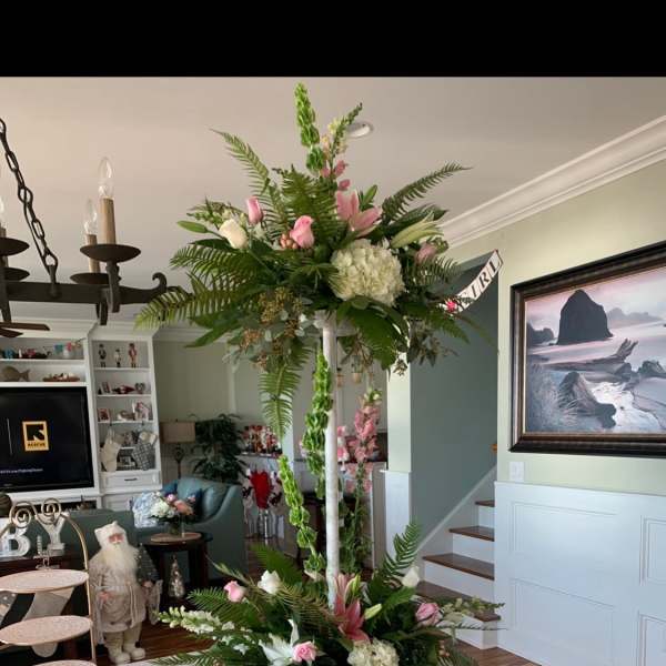 Tall floral centerpiece with pink and white blooms on a table