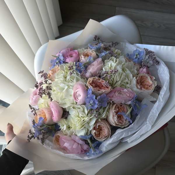 Hand-tied bouquet of pastel pink, peach, blue, and white flowers