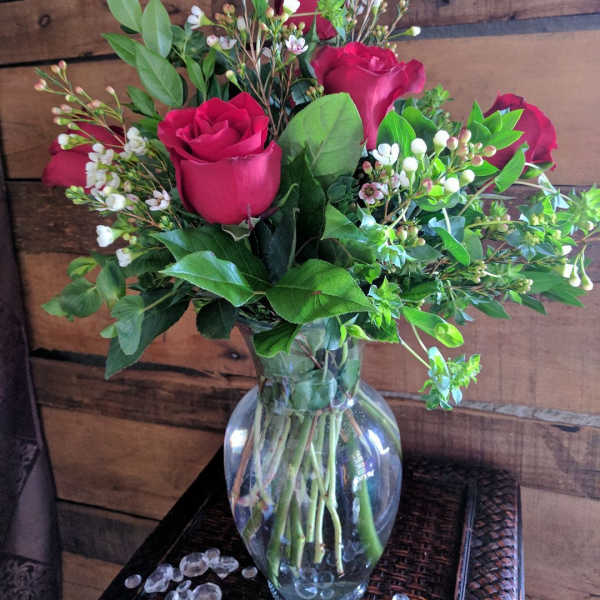 Bouquet of red roses and white filler flowers in a clear glass vase