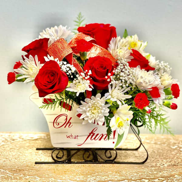 Red roses and white daisies in a decorative container with a ribbon