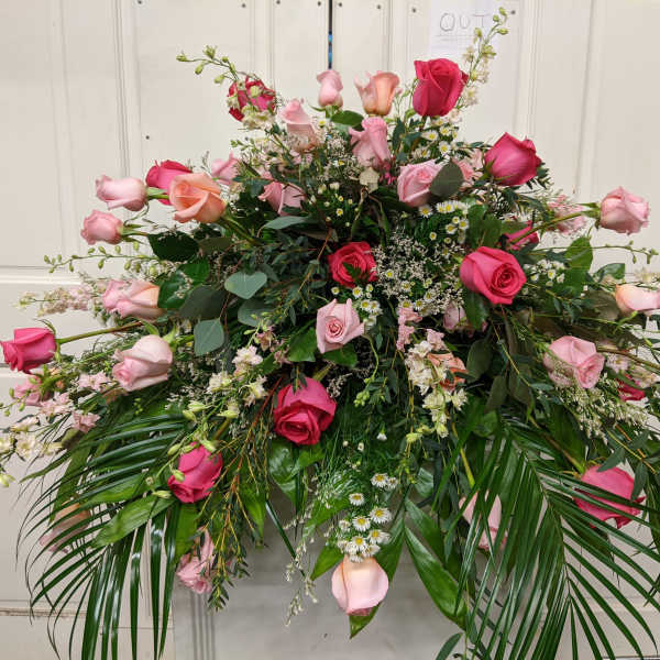 Large pink and red rose arrangement with cascading greenery
