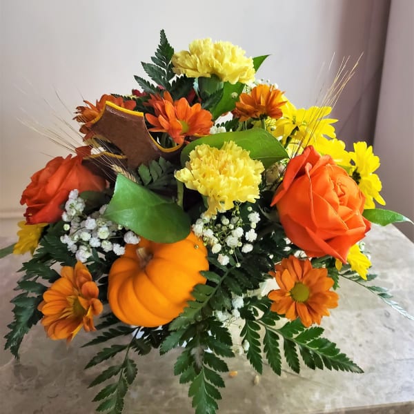 Orange and yellow flower arrangement with a small pumpkin centerpiece
