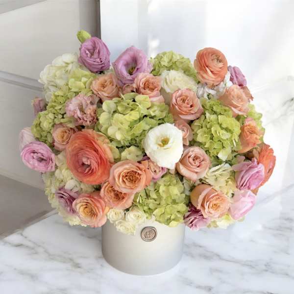 Pastel bouquet of roses, ranunculus, and hydrangeas in a white hat box