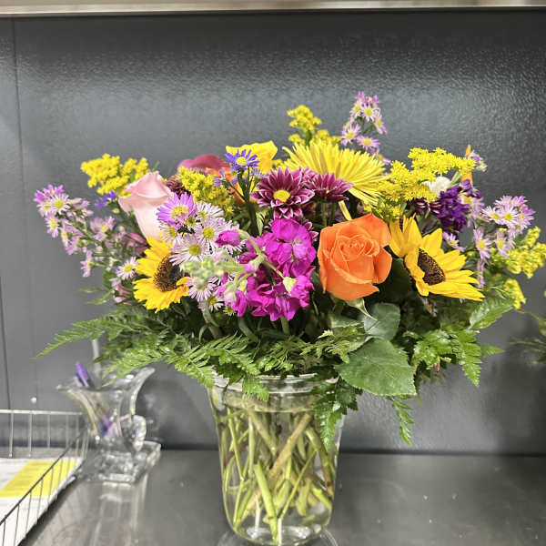 Mixed bouquet of bright flowers in a clear glass vase