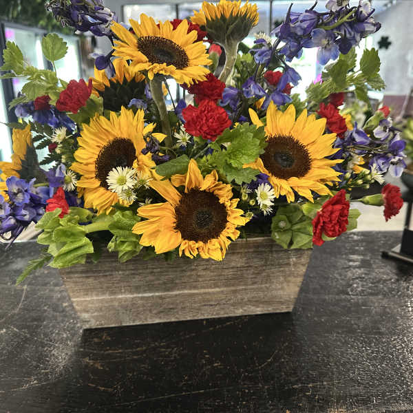 Sunflower arrangement with purple and red flowers in a rectangular wooden planter