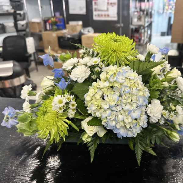 Low floral arrangement with blue hydrangea, green chrysanthemums, and white blooms