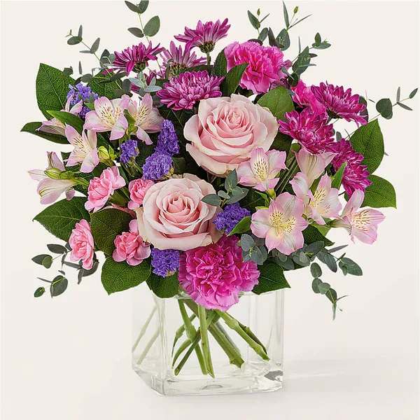 Pink roses and mixed blooms in a clear glass vase