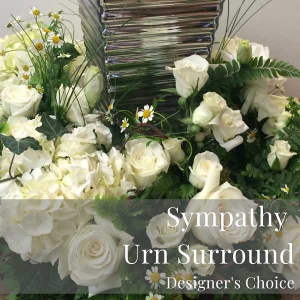 White roses and daisies arranged around a silver urn.