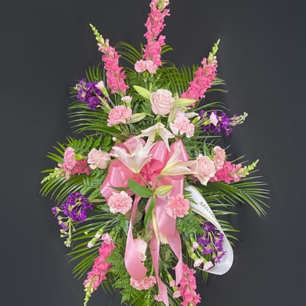 Pink and purple funeral spray with lilies and roses on a stand