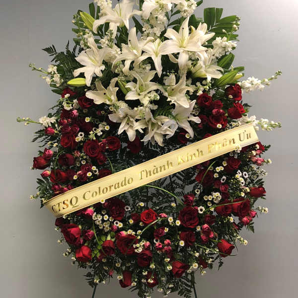 Standing floral wreath with white lilies and red roses on an easel