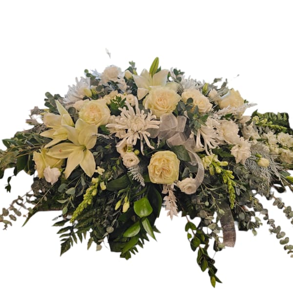 Cream floral casket spray with roses, lilies, and white blooms