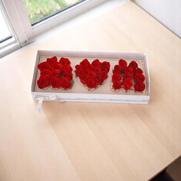 Boxed arrangement of red roses arranged as three letters