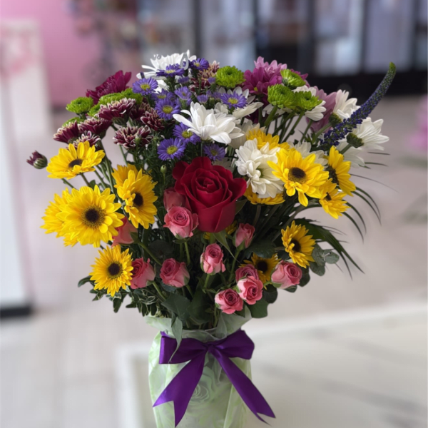 Mixed bouquet of roses, daisies, and chrysanthemums in a wrapped vase
