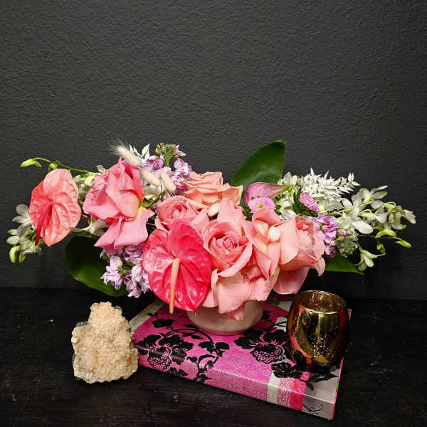 Pink floral arrangement in a low vase with roses and anthuriums