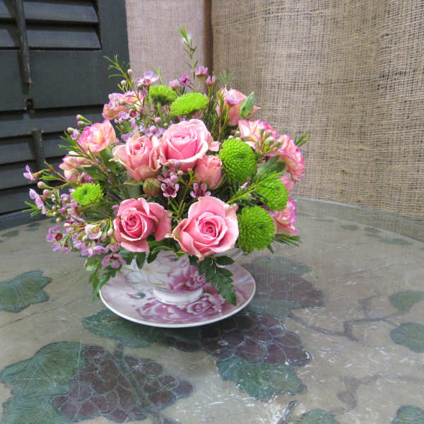 Pink rose bouquet in a floral teacup and saucer