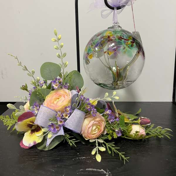 Pastel floral arrangement with roses and purple accents beside a hanging glass ornament
