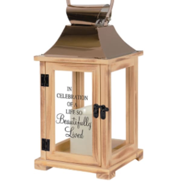 Wooden memorial lantern with metal top, glass panels, and candle inside.