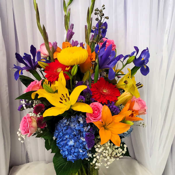 Colorful mixed bouquet in a glass vase with lilies, roses, gerberas, and hydrangea