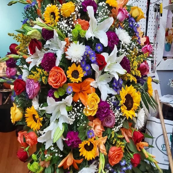 Large colorful floral arrangement with lilies, roses, and sunflowers