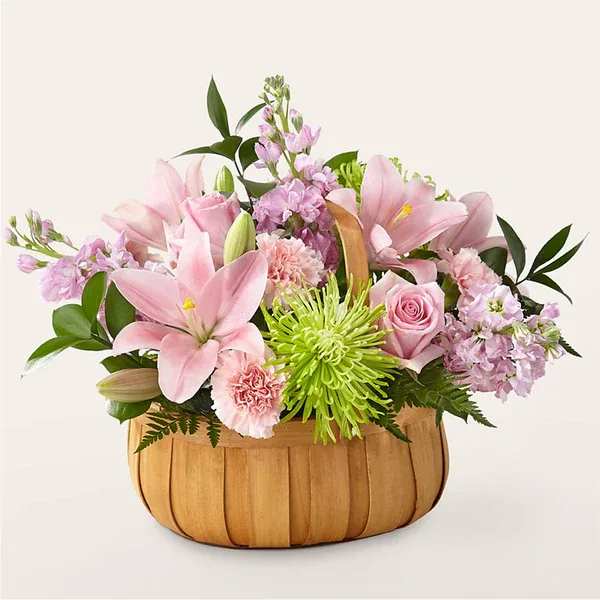 Pink lilies and roses in a wooden basket with green accents