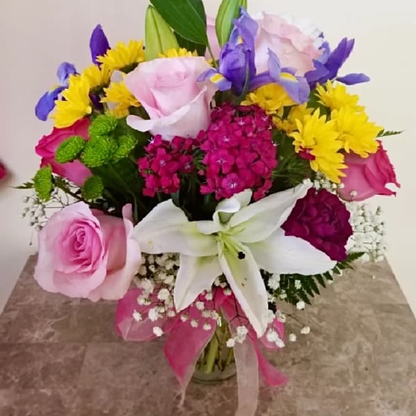 Mixed bouquet with pink roses, white lily, yellow daisies, and purple irises
