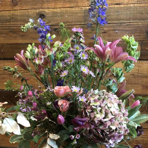 Mixed bouquet of pink lilies, roses, and hydrangea in a glass vase